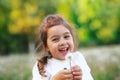 Pretty  little girl  is smiling in the park with dandelion flower. Happy cute kid having fun outdoors at sunset Royalty Free Stock Photo