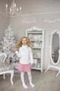 Pretty little girl stands and touches her hair in a light new year decoration studio