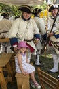 Pretty little girl surrounded by men standing dressed as 18th Century French soldiers Royalty Free Stock Photo