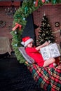 Pretty little girl on a suspended chair in the Christmas decor opens a gift from Santa in the box. New Year, 2020, Christmas Royalty Free Stock Photo