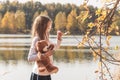 Pretty little girl with teddy bear holds dry leaf on forest lake on autumn day. Royalty Free Stock Photo