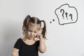 pretty little girl with two ponytails is standing in a pensive pose on a light background. Royalty Free Stock Photo