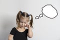 pretty little girl with two ponytails is standing in a pensive pose on a light background Royalty Free Stock Photo