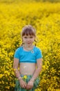 Pretty little girl walking with blue dress in boho style in rapeseed field. Cute young lady model in summer sunny day Royalty Free Stock Photo