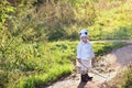 Pretty little girl in white stands with stick