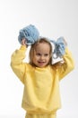 Pretty little girl in yellow clothes plays with ball of blue thread. Child model with long blond hair sits in studio on Royalty Free Stock Photo