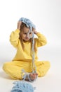 Pretty little girl in yellow clothes plays with ball of blue thread. Child model with long blond hair sits in studio on Royalty Free Stock Photo