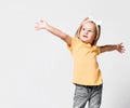 Pretty little kid baby girl in yellow t-shirt is singing with her hands up spread, dancing, playing role, makes show Royalty Free Stock Photo