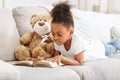 Pretty little kid laying on sofa and reading book Royalty Free Stock Photo