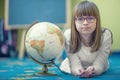 Pretty little student girl studying geography with globe in a child's room Royalty Free Stock Photo
