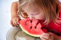 Pretty little toddler girl 4 year eating watermelon close-up at home. Funny blond child portrait with watermelon indoors, view up Royalty Free Stock Photo