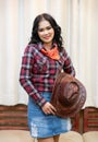 Pretty long black hair asian woman wearing plaid shirt with cowboy bandana and cowboy hat on Curtain background.