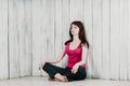 A girl in a pink top, sitting cross-legged on the floor, light b Royalty Free Stock Photo