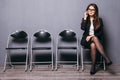 Pretty lovely manager lady using mobile phone calling and sitting on wood floor chair in gray wall background room waiting for int Royalty Free Stock Photo