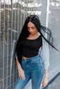 Pretty luxury young hipster woman in a summer cape in a trendy black top in jeans with long black hair in stylish sunglasses Royalty Free Stock Photo