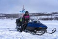 Pretty middle aged Caucasian Scandinavian women with mobile in palm sits on snowmobile in Lapland mountains. Winter outdoor travel