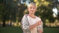 Pretty middle aged woman drinking water in park, keeping water balance, health Royalty Free Stock Photo