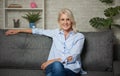 Pretty middle aged woman is sitting on a sofa at home Royalty Free Stock Photo