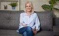 Pretty middle aged woman is sitting on a sofa Royalty Free Stock Photo