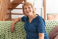 Pretty middle aged woman sitting on sofa in room Royalty Free Stock Photo