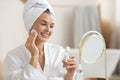 Pretty middle aged woman using face tonner, looking at mirror Royalty Free Stock Photo