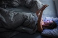 Pretty, middle-aged woman using her cell phone in bed at night Royalty Free Stock Photo