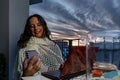 pretty middle aged woman using laptop and smart phone at same time on outdoor balcony at sunset