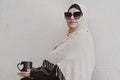 Pretty middle eastern girl in traditional Islamic clothing, drinking cup of coffee. Cute Arabian woman holding a cup of hot