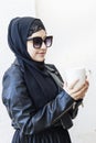 Pretty middle eastern girl in traditional Islamic clothing, drinking cup of coffee. Cute Arabian woman holding a cup of hot