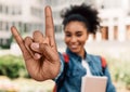 Pretty millennial female student showing big rock gesture at college campus, outdoors. Teen music concept