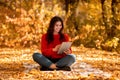 Pretty millennial woman in warm autumn outfit browsing internet on tablet computer at park Royalty Free Stock Photo