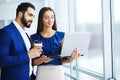 Pretty mixed race woman and her bearded colleague using laptop i Royalty Free Stock Photo