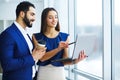 Pretty mixed race woman and her bearded colleague using laptop i Royalty Free Stock Photo