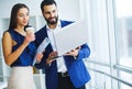 Pretty mixed race woman and her bearded colleague using laptop i Royalty Free Stock Photo