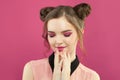 Pretty model woman with fashion makeup, trendy manicure nails and topknot haircut on bright pink background