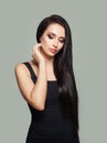 Pretty model woman with long straight hair and makeup wearing black dress posing against gray wall background Royalty Free Stock Photo