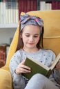 Pretty and modern school girl reading a book at home library Royalty Free Stock Photo