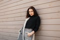 Pretty modern young woman in a black T-shirt in a gray fashionable checkered jacket in stylish vintage pants resting on the street Royalty Free Stock Photo