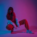 Pretty modern young woman dancer in fashionable youth clothes in a white sneakers sits in a room with bright pink light. Sporty Royalty Free Stock Photo