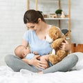 Pretty mom showing soft teddy bear to her newborn baby Royalty Free Stock Photo