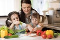 Pretty mother and her kids making vegetable salad Royalty Free Stock Photo