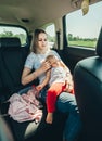 Pretty mother hugging sleeping daughter in the arms on her chest in the car. She taking care her baby with love Royalty Free Stock Photo