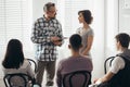 Mother stands next to handsome therapist talking to her teenage child during group meeting Royalty Free Stock Photo