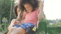 Pretty mother swinging her beloved daughter in backyard, family happiness