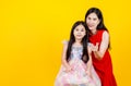 Pretty mother tenderly hug cute young daughter with love and care as sweetheart, together smile and pose to camear against yellow