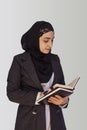 Pretty Muslim businesswoman in hijab holding stack of business documents, notepads. Woman doing business in Islamic word, or Royalty Free Stock Photo