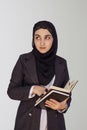 Pretty Muslim businesswoman in hijab holding stack of business documents, notepads. Woman doing business in Islamic word, or Royalty Free Stock Photo