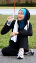 A pretty muslim woman athlete resting while drink