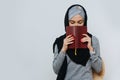 Pretty muslim woman who stands with closed eyes and covers her face with a book Royalty Free Stock Photo