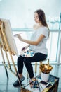 Woman artist painting a picture in a well-lit studio Royalty Free Stock Photo